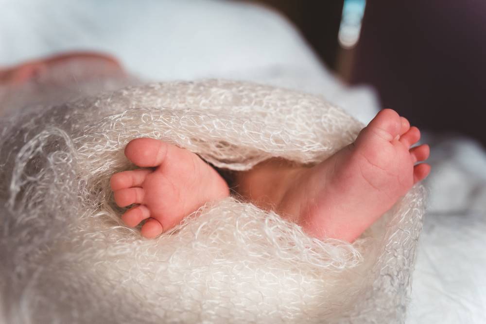 Des pieds de bébé dépassent d'une douce couverture en laine